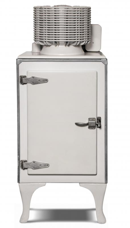 An antique refrigerator with the compressor assembly on top.