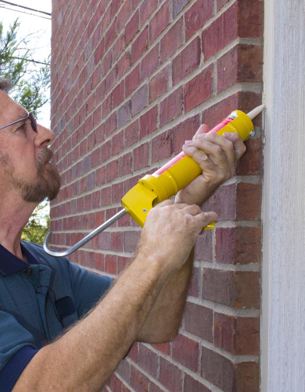Applying silicone sealant to a wall.