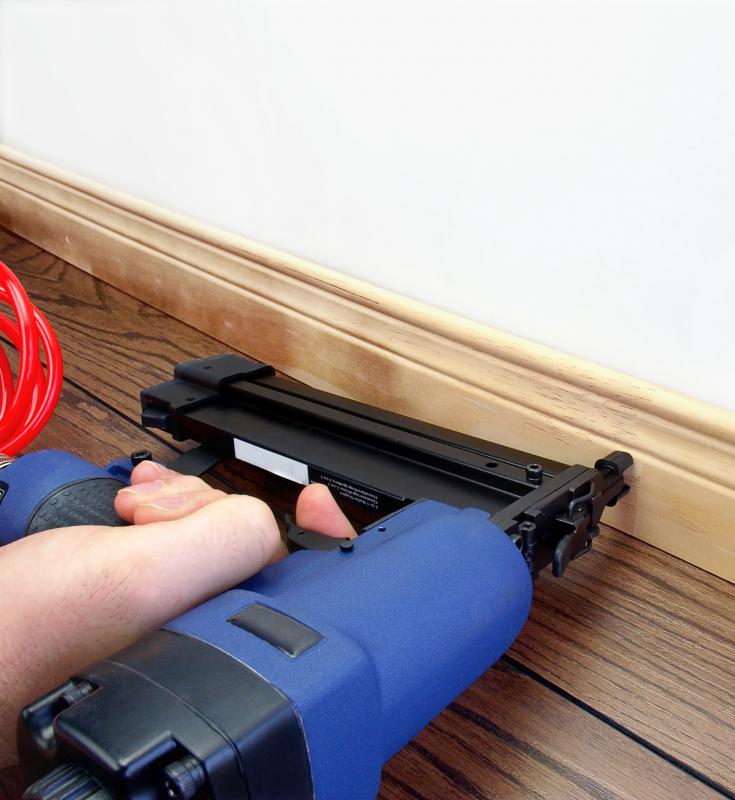 Brad nailer being used to secure baseboard to a wall.