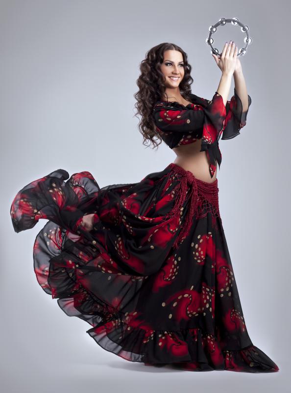 A woman dressed as a gypsy playing a tambourine.