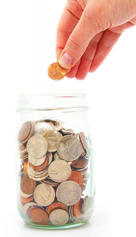 A person dropping a penny in a coin jar.