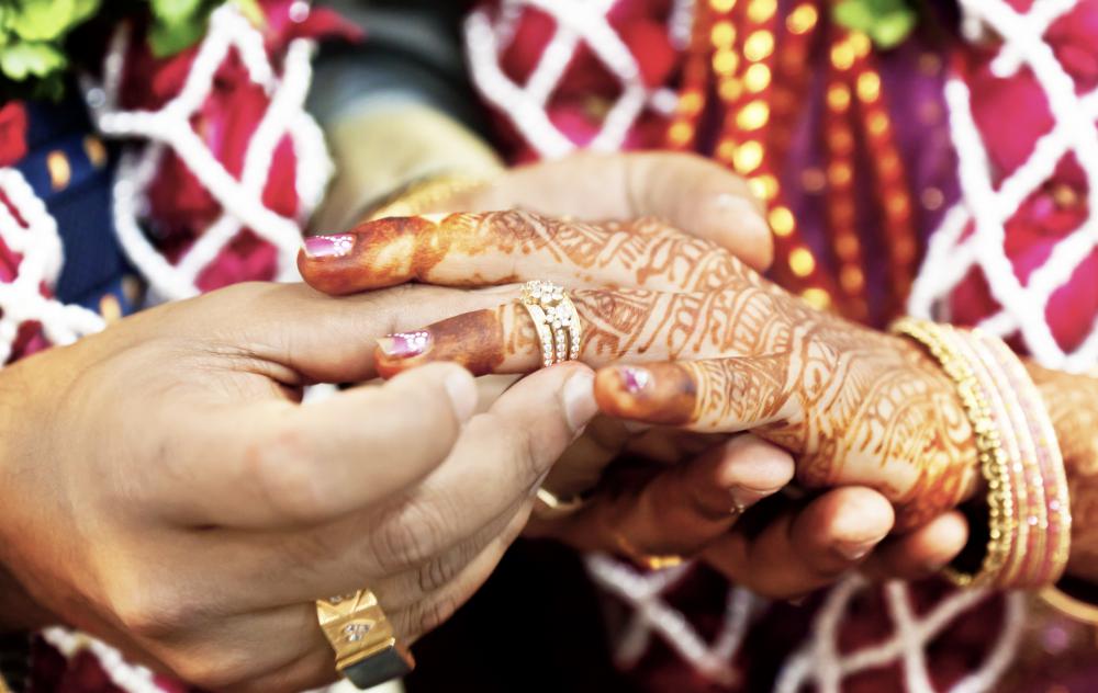 During a mehndi ceremony, henna paste is applied to a bride's hands and feet in intricate patterns.