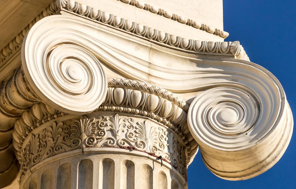 An Ionic capital is characterized by its spiraled scroll design, called volutes.