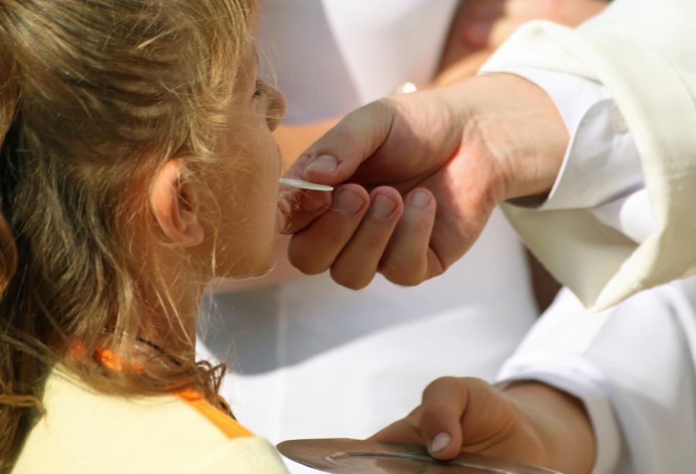 Priest giving the Holy Communion to a young girl.