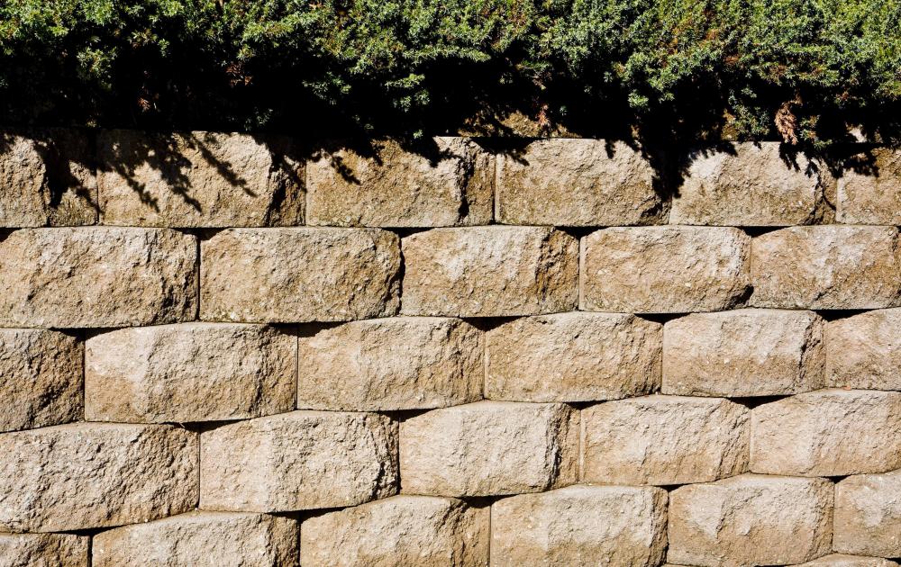 Retaining walls use sturdy material, such as concrete blocks, to hold sloping ground in place.