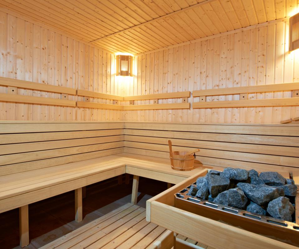 A steam bath room with wooden benches and sauna stones.